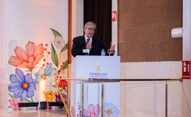 Un hombre habla desde un podio decorado con flores en un evento formal.