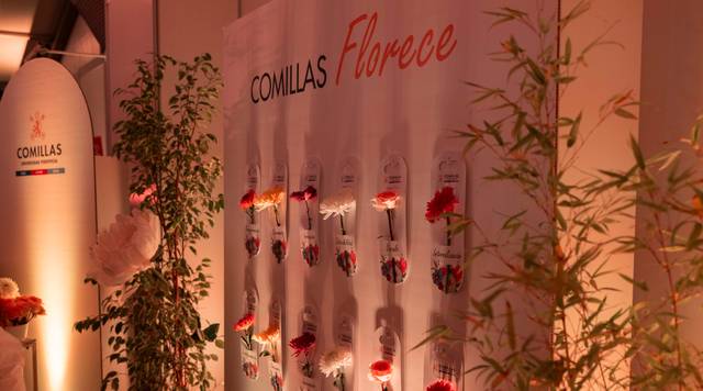 Un evento decorado con un fondo donde se exhiben flores junto a la palabra 'COMILAS Florece'.