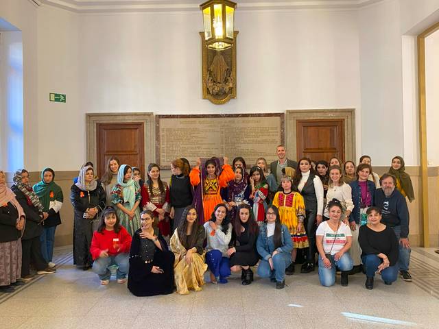 Un grupo diverso de mujeres posando juntas en un espacio interior con paredes de piedra.