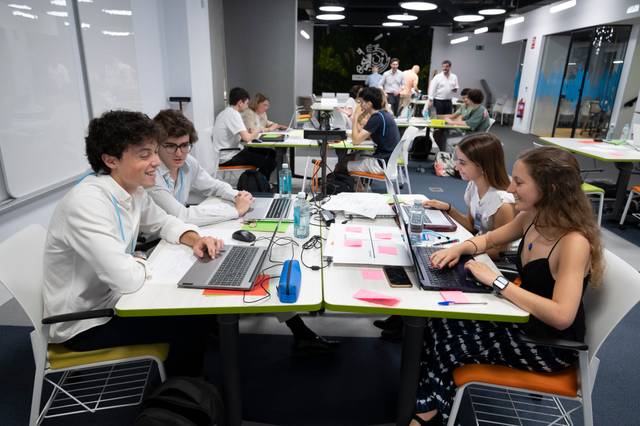 Un grupo de estudiantes trabaja en sus computadoras portátiles en un ambiente colaborativo.