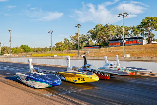 Tres vehículos de carreras se alinean en una pista bajo un cielo despejado.