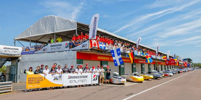 Un grupo de personas celebra un evento relacionado con automóviles en una pista de carreras.