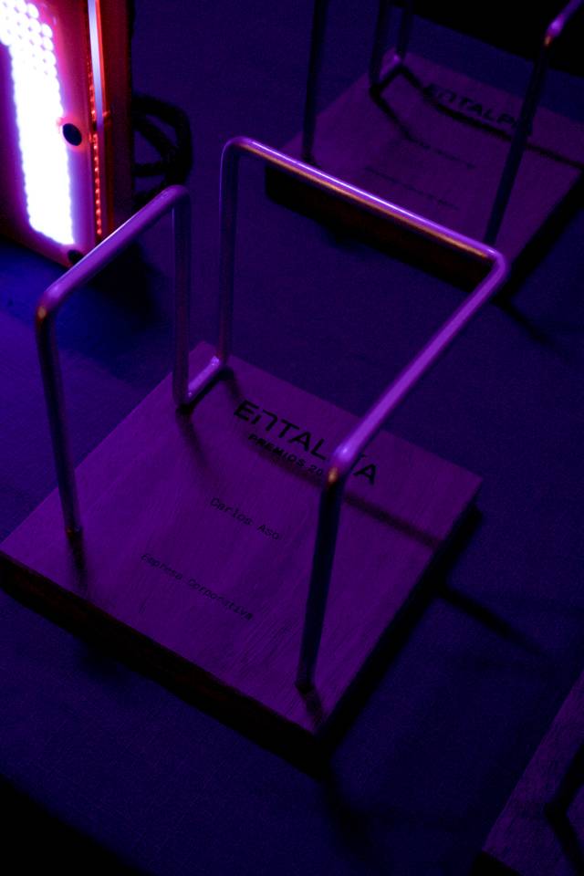 La imagen muestra estructuras metálicas sobre bases de madera en un ambiente iluminado con luz morada.