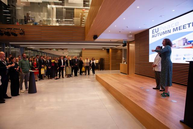 A person addresses an attentive audience in a modern conference room during an EU event.