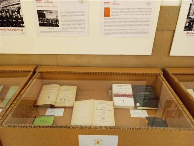 La imagen muestra una vitrina con libros y documentos sobre mecánica cuántica en una exposición.