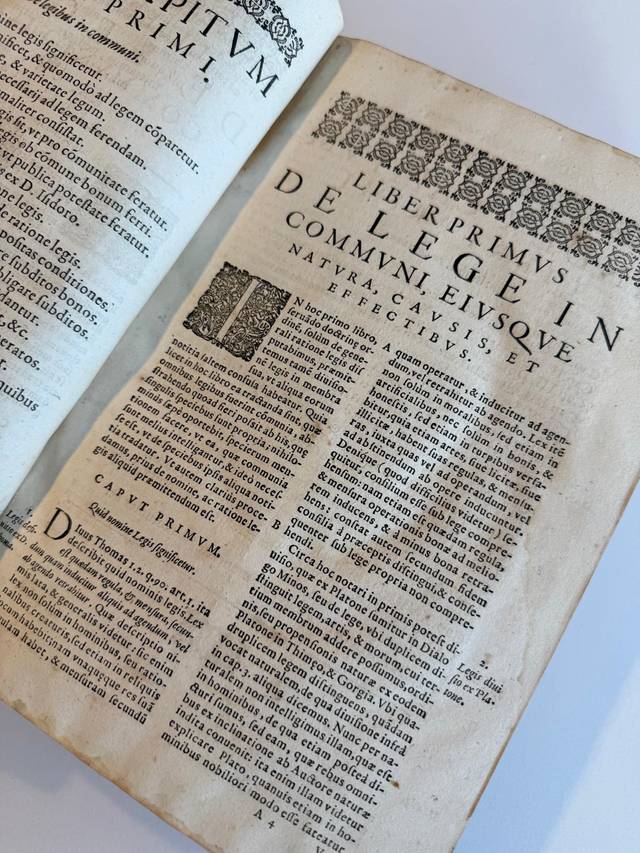 Un libro antiguo abierto que contiene texto en latín y diversos elementos gráficos.