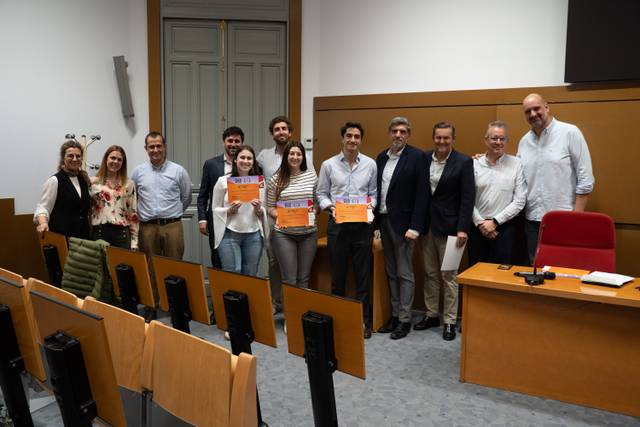 Un grupo de personas posando en una sala después de un evento, sosteniendo certificados.