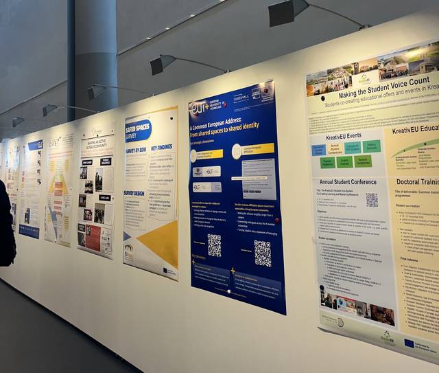 La imagen muestra una serie de paneles informativos expuestos en una pared blanca en un evento o conferencia.