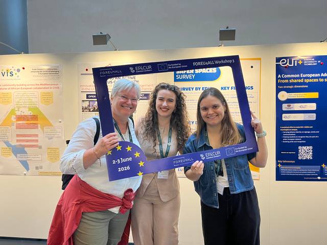 Tres mujeres sostienen un marco de fotos en un evento, sonriendo y mostrando su participación.