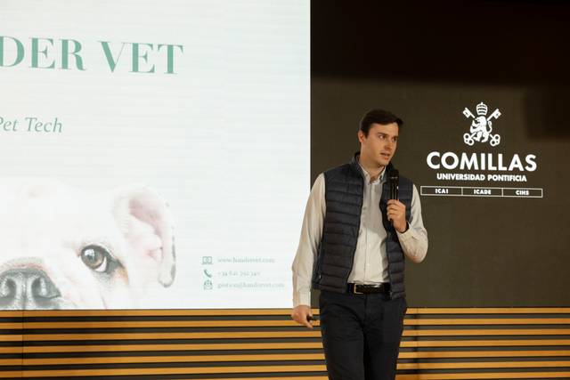 Un hombre presenta una charla sobre tecnología veterinaria en un auditorio.