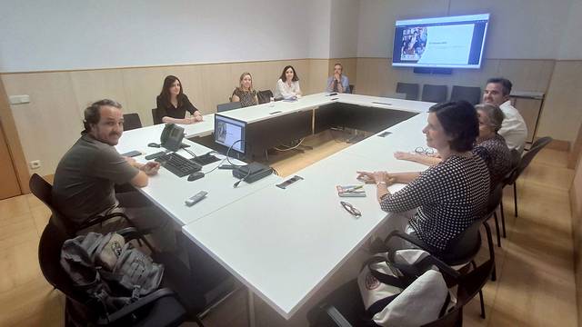 Un grupo de personas reunidas en una sala de conferencias alrededor de una mesa rectangular.