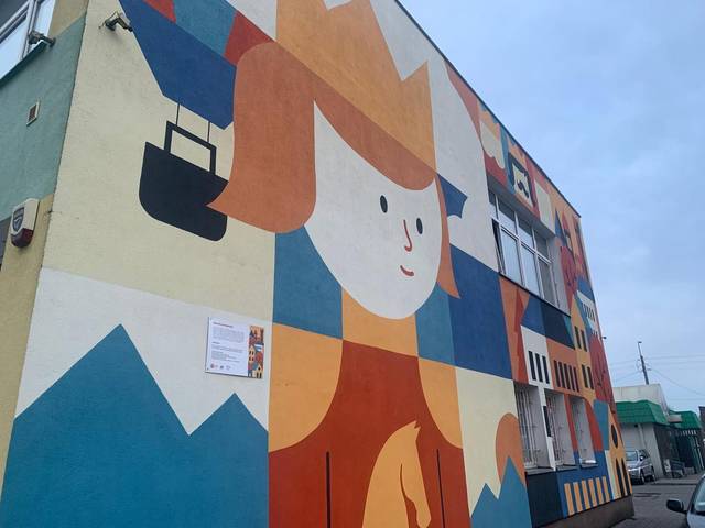 Una colorida pintura mural de un personaje con un sombrero en un edificio.