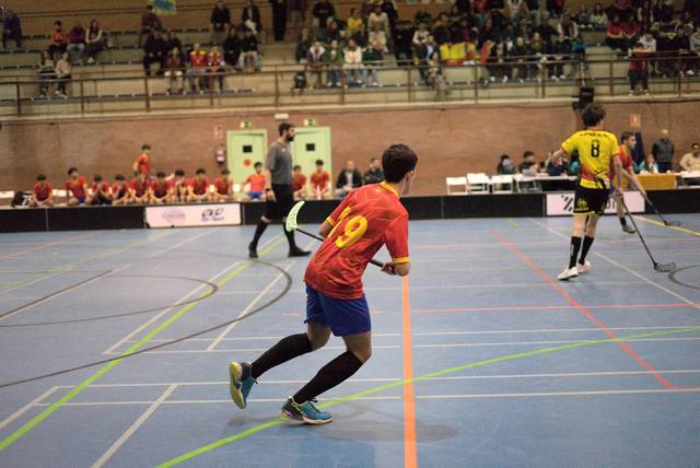 Jugador con el número 19 corriendo en una cancha de balonmano durante un partido.