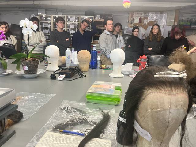 Una clase sobre peluquería con varias cabezas de maniquí y estudiantes observando.