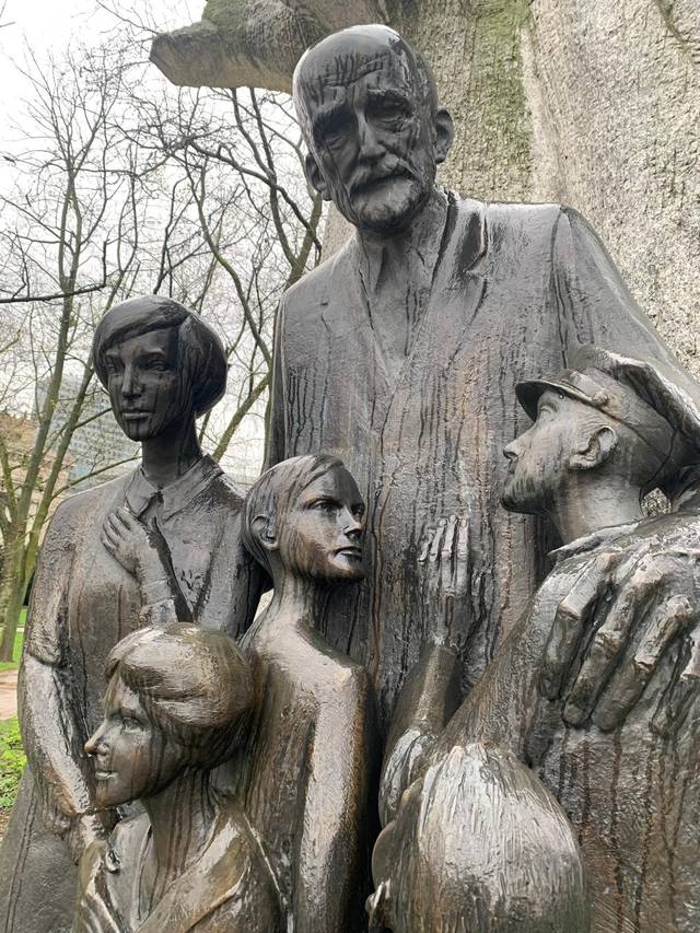 Escultura que representa a varias figuras humanas en un entorno natural.