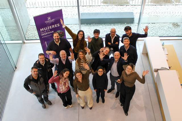 Grupo de personas sonriendo y saludando con entusiasmo en un espacio moderno.