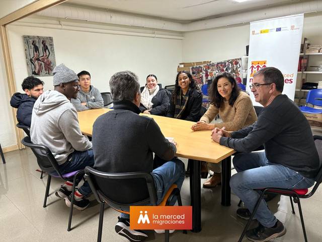 Un grupo de personas se reúne alrededor de una mesa en un ambiente de trabajo colaborativo.