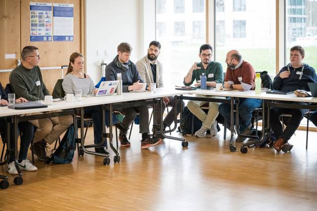 Un grupo de personas sentadas alrededor de una mesa en una reunión.