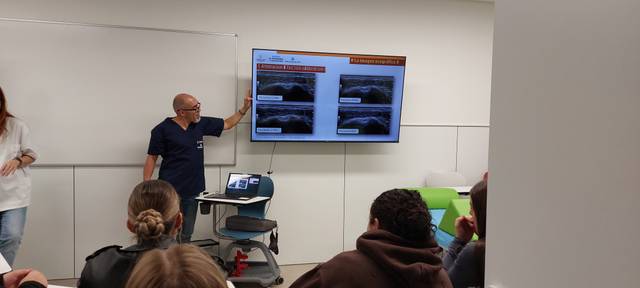 Un médico presenta información en una pantalla durante una clase o conferencia.