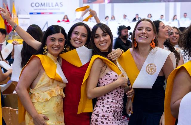 Un grupo de cuatro mujeres sonrientes celebrando en un evento de graduación.