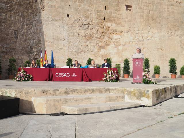 Un evento formal con una mesa en el escenario donde se presentan varios oradores frente a un fondo histórico.
