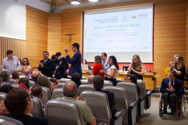 El acto de imposición de becas celebra la 12ª promoción con los asistentes aplaudiendo.