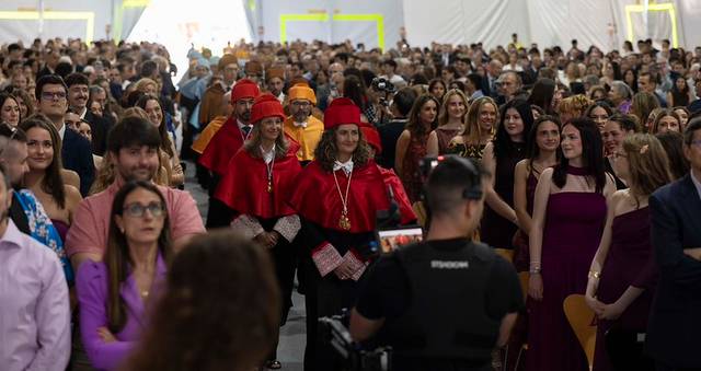 Un gran grupo de personas se reúne en un evento, con algunos asistentes vistiendo trajes llamativos al frente.