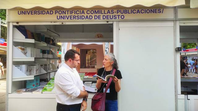 A man and a woman discussing books at a university publication stall.