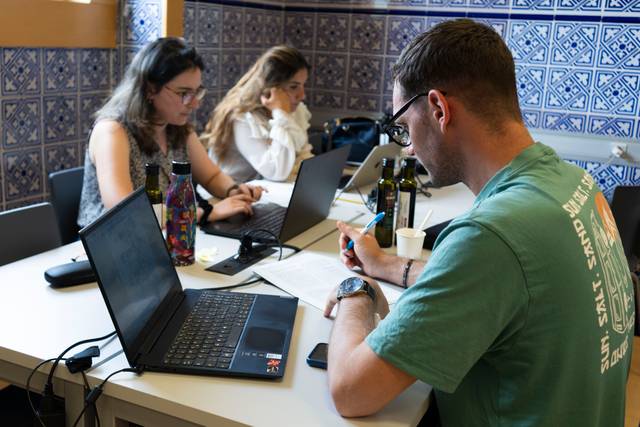 Tres personas trabajando en un ambiente de estudio con computadoras y material de oficina.