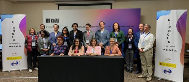 Grupo de personas posando para una fotografía en una sala con banners publicitarios de eventos científicos, firman el acuerdo de Guadalajara en la FIL 2024.