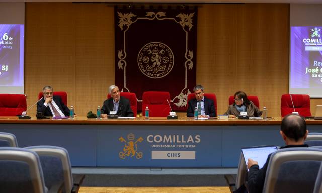 Una mesa de debate en una universidad con varios ponentes presentando información.