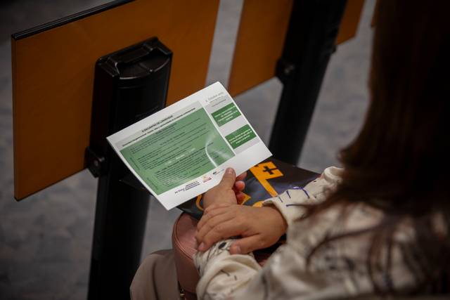 Una persona sostiene un folleto en un ambiente de reunión o conferencia.