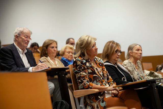 Un grupo de personas sentadas en un auditorio prestando atención durante una charla.