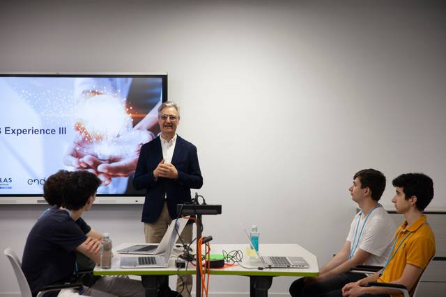 Un hombre presenta en una sala de conferencias frente a un grupo de jóvenes que están sentados con computadoras portátiles.