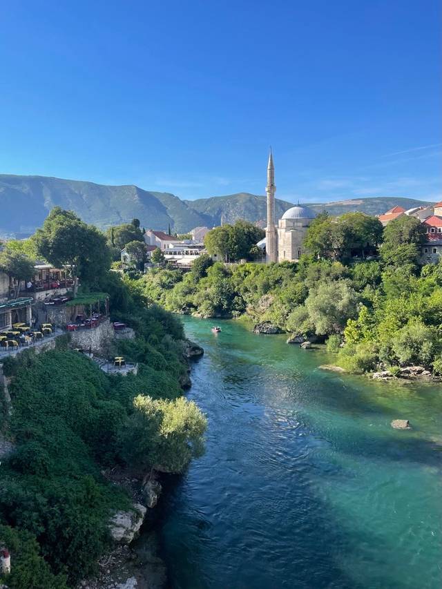 Vista de un río rodeado de vegetación y una mezquita bajo un cielo despejado.