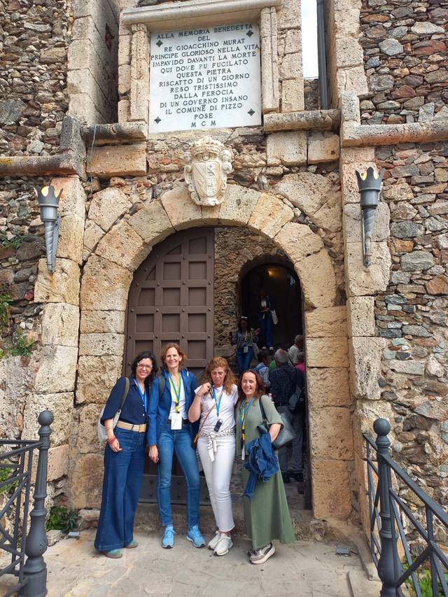 Cuatro mujeres posando frente a una puerta de piedra en un entorno arquitectónico histórico.