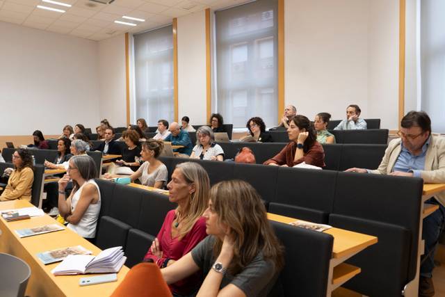 Un grupo de personas sentadas en una sala de conferencias prestando atención a una presentación.