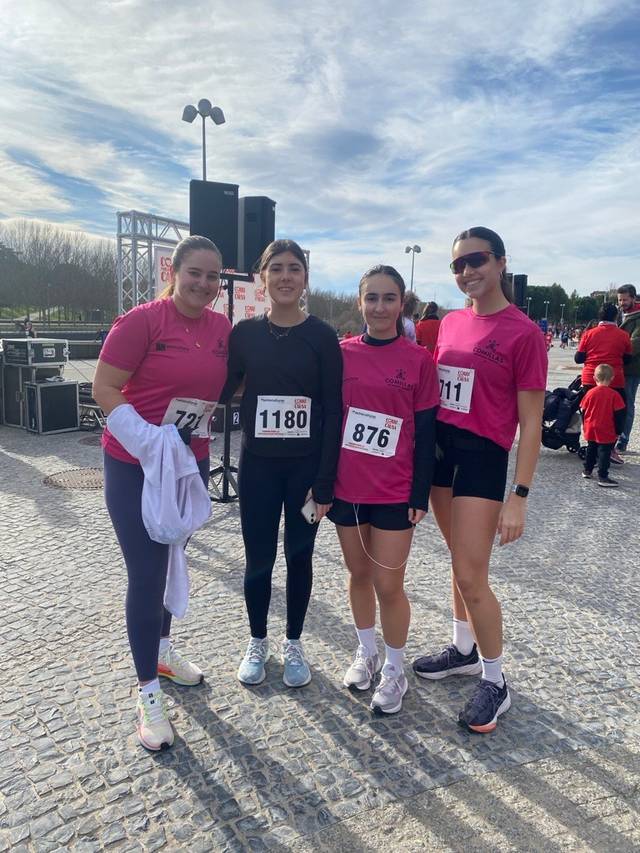 Cuatro jóvenes se preparan para una carrera, vestidas con camisetas rosas y números en el pecho.