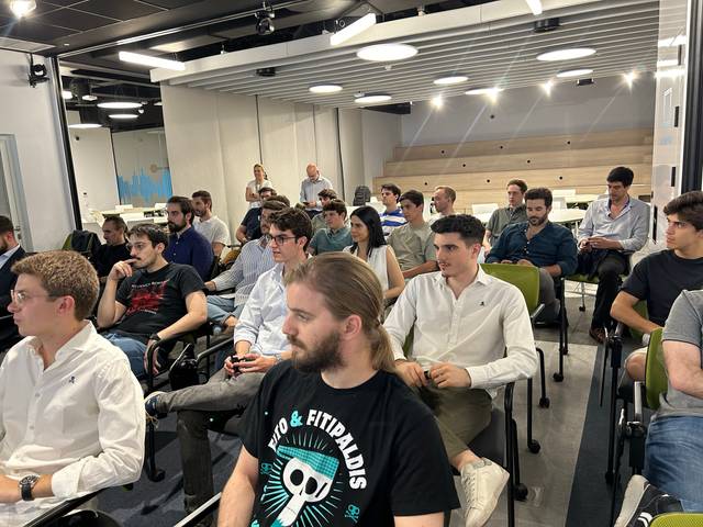 A group of people seated in a conference room, attentively listening to a presentation.