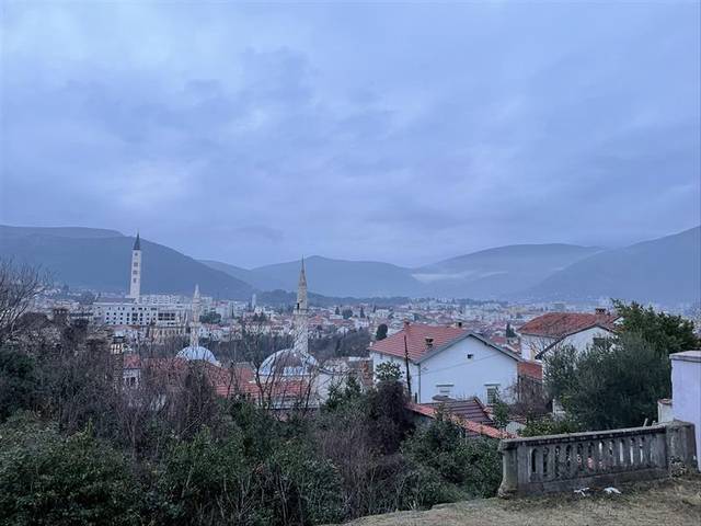 Vista panorámica de una ciudad rodeada de montañas bajo un cielo nublado.