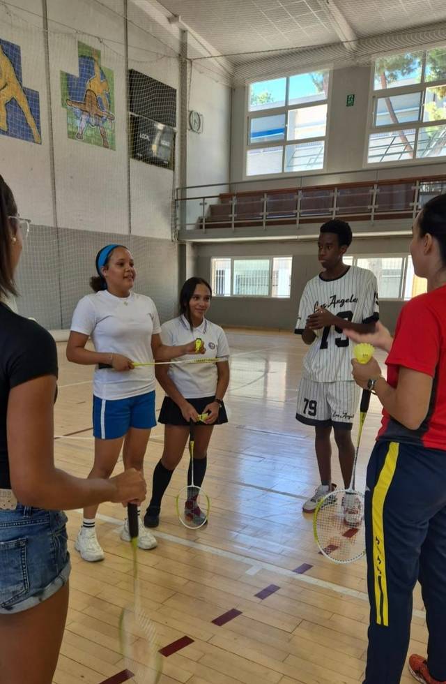 Un grupo de jóvenes se reúne en un gimnasio para practicar una actividad deportiva.