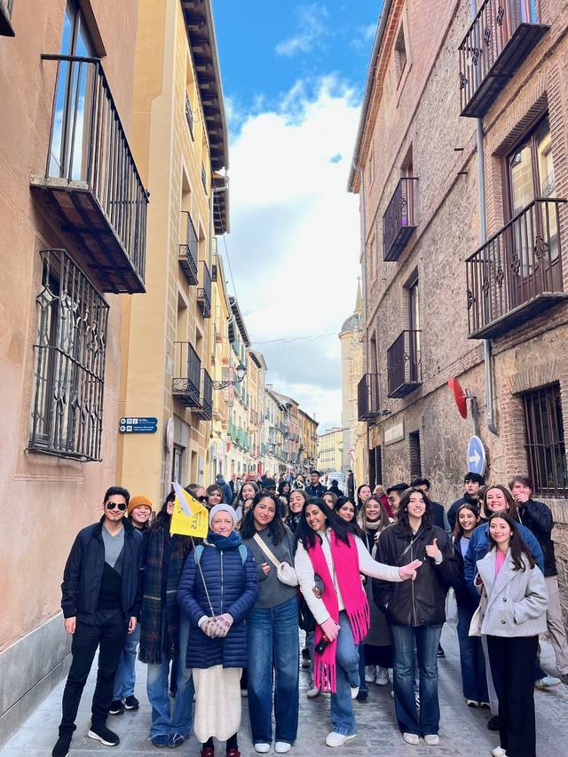 Grupo de personas sonriendo en una calle estrecha con edificios antiguos a ambos lados.