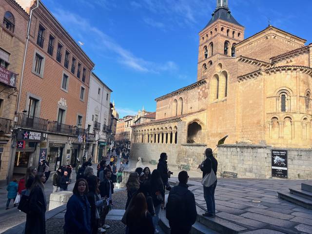 Una vista de una plaza concurrida con gente y una iglesia al fondo durante el día.