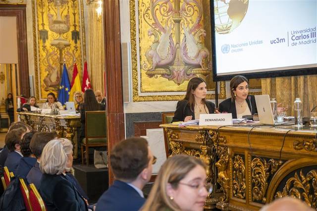 Dos mujeres están presentando en un evento en un ambiente formal.