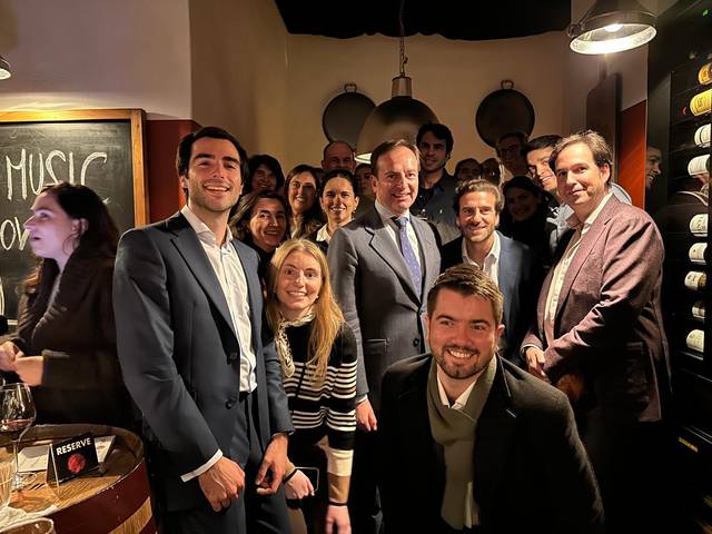 A group of people smiling in a wine bar with a chalkboard in the background.