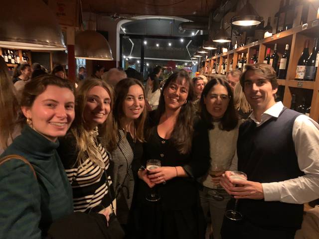 A group of six friends enjoying a social gathering at a wine bar.