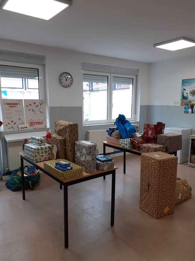 Una habitación con varias mesas llenas de regalos envueltos de colores diferentes.