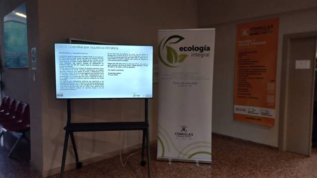 La imagen muestra una pantalla digital con información sobre ecología y un cartel de presentación en un entorno académico.