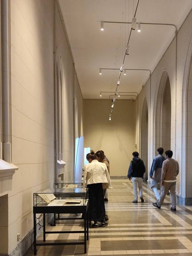 Un grupo de personas observa muestras en un pasillo de un museo.