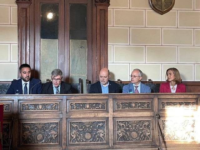 Un grupo de personas sentadas en un panel durante un evento en un salón decorado.